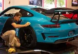 Technician performing precision paintless dent repair on a teal Porsche 911 GT3 RS in a professional workshop