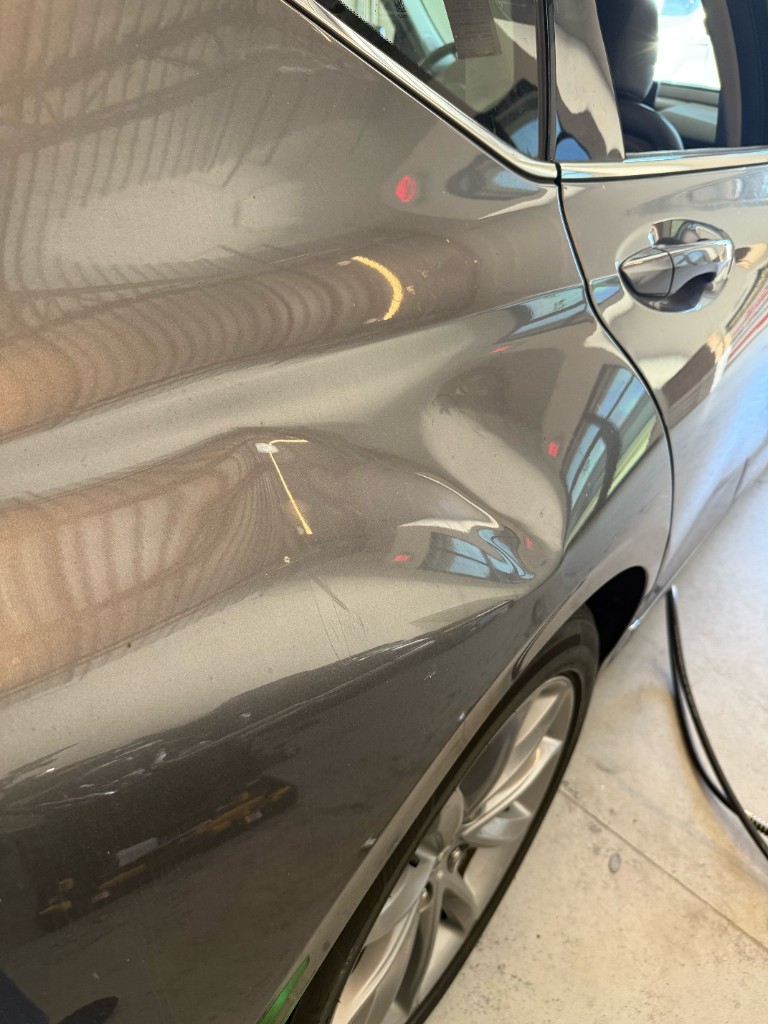 Extreme dent on a gray car rear quarter panel with major panel deformation