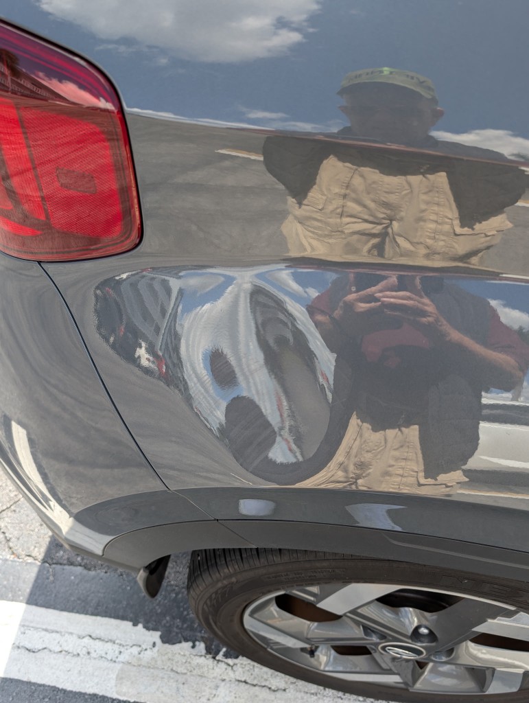 Large deep dent on a dark gray car rear quarter panel near the taillight