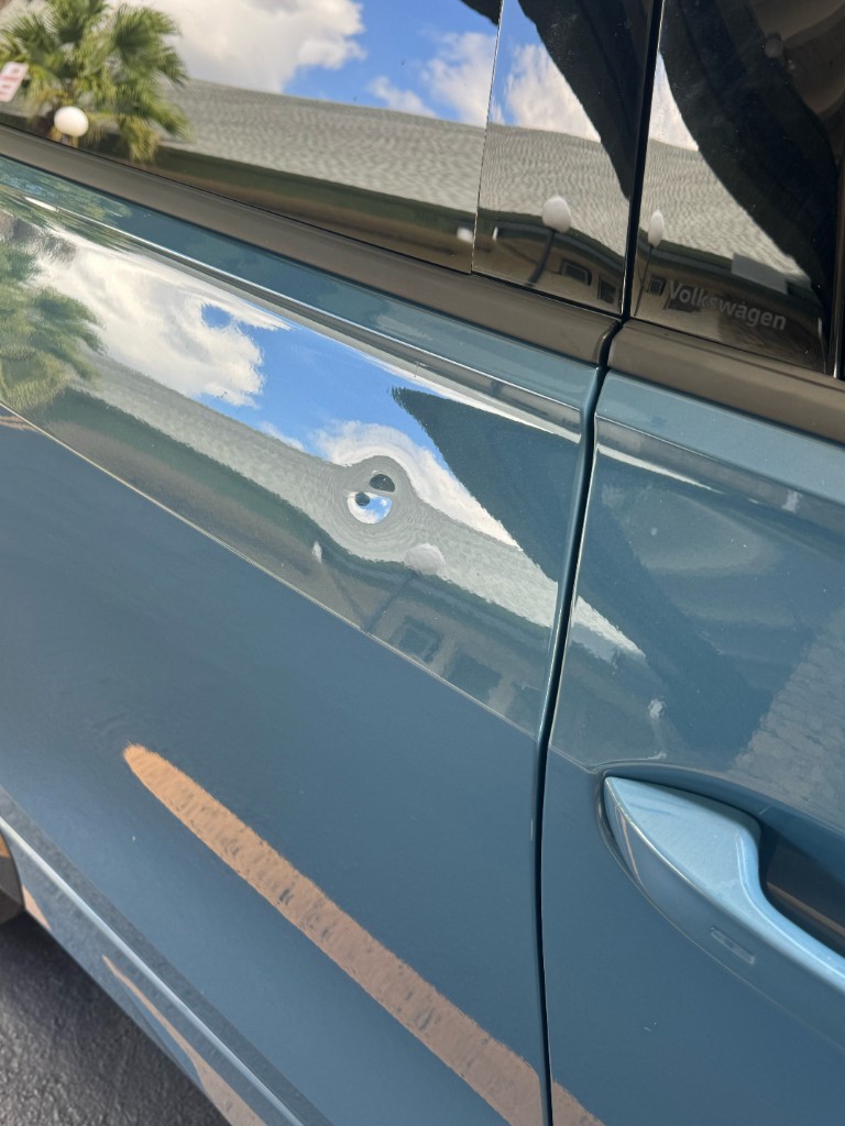 Small dent example on a light blue-grey car door near the handle