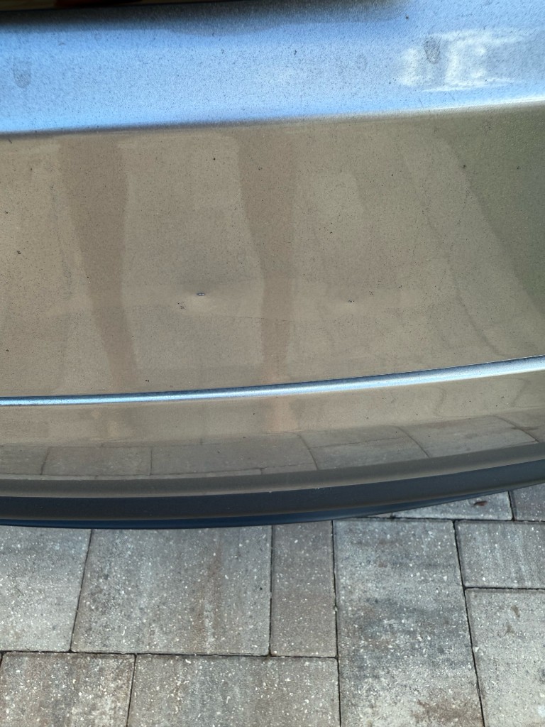 Small paint chips and dimples on a silver car bumper